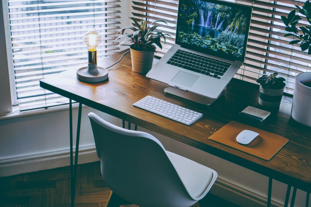 A tidy home office setup with desk, laptop and plants.